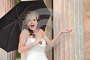 Beautiful bride holding umbrella in rain