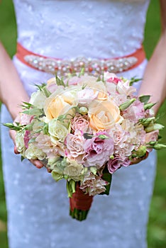 Beautiful bride is holding a wedding colorful bouquet