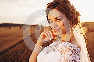 Beautiful bride in a lace dress is smiling on the background of nature