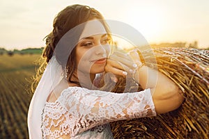 Beautiful bride in a lace dress is smiling on the background of nature