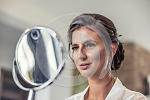 Beautiful bride looking into the mirror on her wedding day preparation