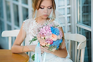 The beautiful bride lowered her eyes to her bouquet of flowers. A girl in a white dress admires the roses.