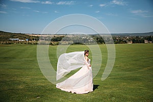 Beautiful bride in luxury fashion white wedding dress with veil on the green golf club glade, wedding day. Amazing full