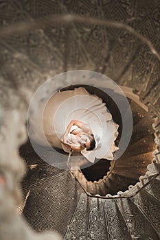 Beautiful bride in magnificent dress stands alone on stairs