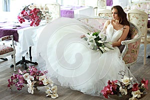 Hermoso novia en magnífico blanco boda ropa de tul corsé sobre el sofá lirio orquídea 