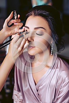 A beautiful bride makeup artist applies makeup. Wedding morning of the bride