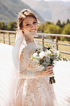 Beautiful bride in a nice dress stands on the terasse with great mountain view in Georgia