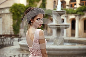 Beautiful bride with pearl earrings jewelry wears pink prom dress. Outdoor romantic portrait  of Attractive brunette woman with