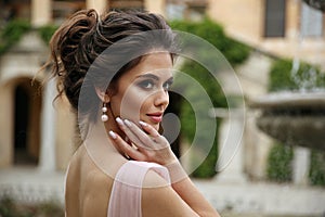 Beautiful bride with pearl earrings jewelry wears pink prom dress. Outdoor romantic portrait  of Attractive brunette woman with