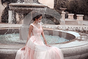 Beautiful bride in pink wedding dress. Outdoor romantic portrait of attractive brunette woman with hairstyle in prom dress with