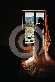 A beautiful bride with pleasant features in a wedding dress poses in the interior of the room. Portrait of the bride in Provence.