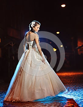 Beautiful bride posing on the evening street in her wedding day