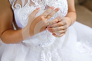 Beautiful bride`s hands on the dress. Fingers with golden rings. Wedding morning