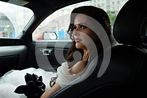 A beautiful bride is sitting in a red car in a white dress and with a bouquet. Wedding Concept