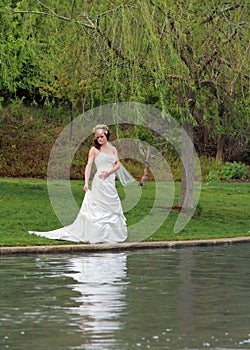 Beautiful bride standing by park river and trees