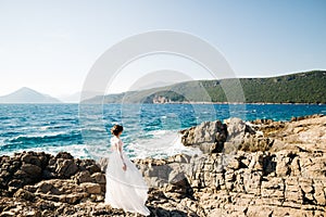 Beautiful bride in tender wedding dress on the rocky beach of the Mamula island