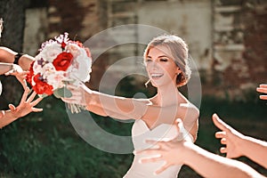 Beautiful bride throws wedding bouquet to her friends