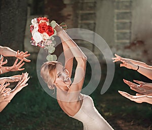 Beautiful bride throws wedding bouquet to her friends