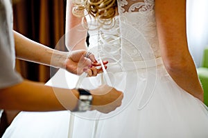 Beautiful bride tying up her wedding dress