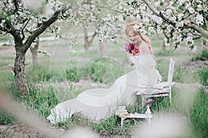 Beautiful bride in a vintage wedding dress posing in a blooming apple garden