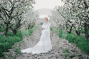 Beautiful bride in a vintage wedding dress posing in a blooming apple garden. Spring mood