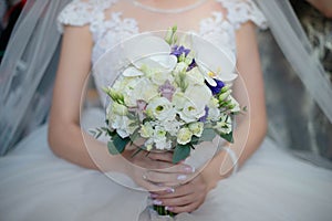 Beautiful bride wearing a gorgeous white dress and veil while holding a beautiful bouquet