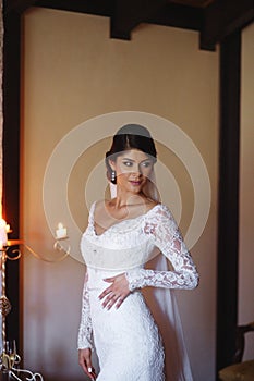 Beautiful bride is wearing a wedding dress. Female portrait in bridal gown for marriage. Cute lady indoors