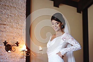 Beautiful bride is wearing a wedding dress. Female portrait in bridal gown for marriage. Cute lady indoors