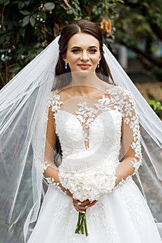 Beautiful bride with a wedding bouquet in their hands outdoors in a park