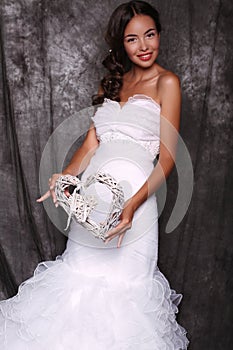 Beautiful bride in wedding dress holding decorative heart