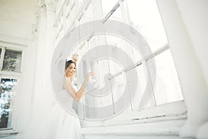 Beautiful bride in wedding dress with long full skirt, white background, dance and smile