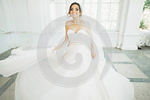 Beautiful bride in wedding dress with long full skirt, white background, dance and smile