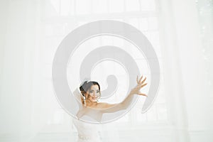 Beautiful bride in wedding dress with long full skirt, white background, dance and smile