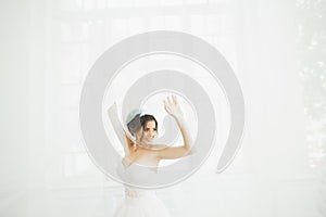 Beautiful bride in wedding dress with long full skirt, white background, dance and smile
