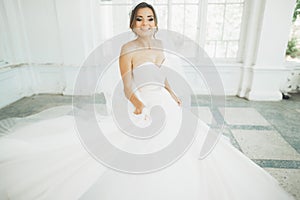 Beautiful bride in wedding dress with long full skirt, white background, dance and smile