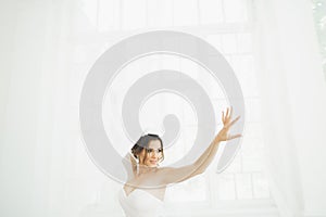 Beautiful bride in wedding dress with long full skirt, white background, dance and smile