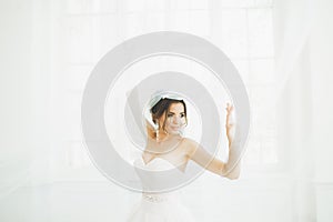 Beautiful bride in wedding dress with long full skirt, white background, dance and smile