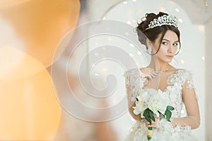 Beautiful bride in a wedding dress at a mirror in Christmas. Girl repeats the hairstyle and makeup.