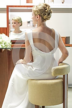 Beautiful bride in a wedding dress at a mirror. Girl prepare the hairstyle and makeup