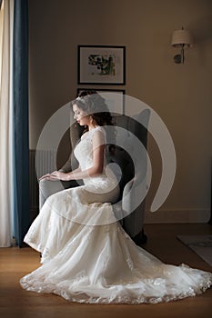 Beautiful bride in wedding dress sitting in a chair in the hotel room