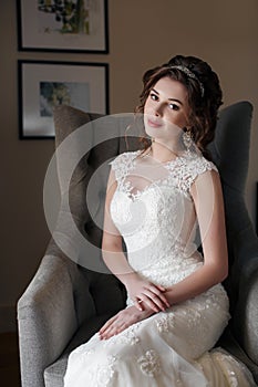 Beautiful bride in wedding dress sitting in a chair in the hotel room