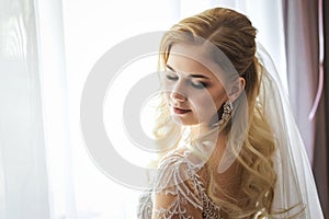 Beautiful bride in a wedding dress standing in front of the window