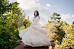 a beautiful bride in a wedding dress whirls and dances on the path in the park.