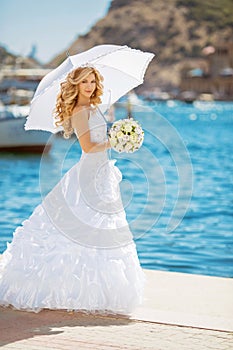 Beautiful bride in wedding dress with white umbrella, outdoors p