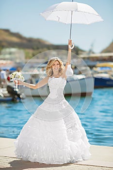 Beautiful bride in wedding dress with white umbrella posing over