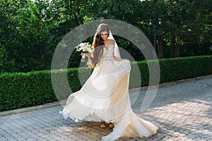 Beautiful bride with wedding flowers bouquet, attractive woman in wedding dress. Happy newlywed woman. Bride with