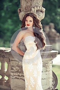 Beautiful bride wedding portrait, vogue style photo. Fashion brunette model posing in prom white dress by roman flower pot, outdo