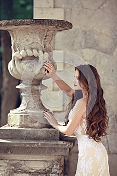 Beautiful bride wedding portrait, vogue style photo. Fashion brunette model posing in prom white dress by roman flower pot, outdo