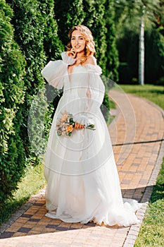 beautiful bride in a white delicate dress on the path in the park.