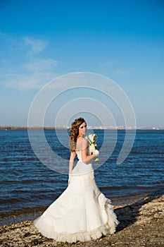 Beautiful bride in a white dress on coast of river